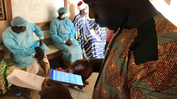 A man collects data from trachoma surgeries on his mobile phone.