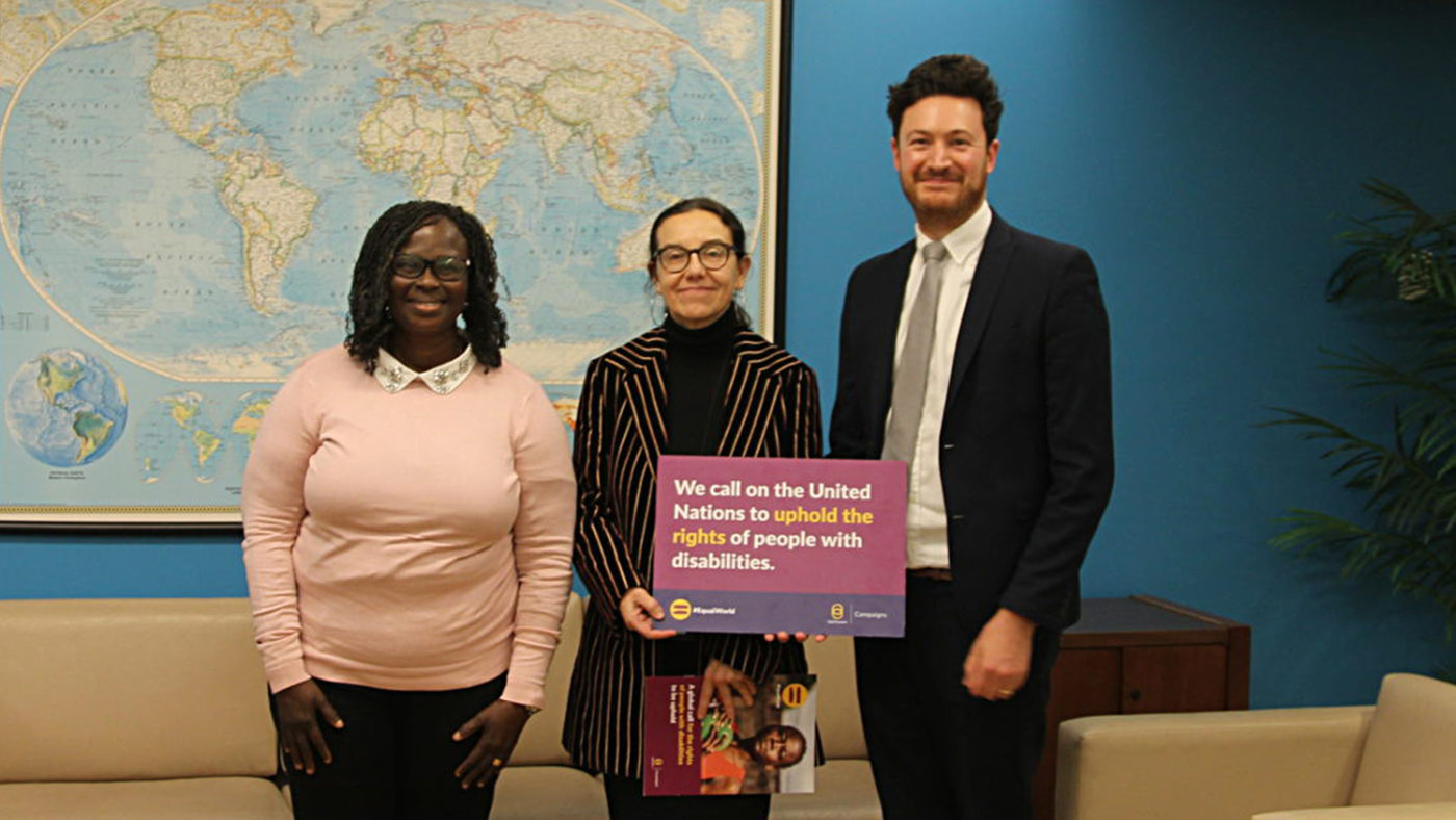 A man and two women stand together, holding a petition sign.