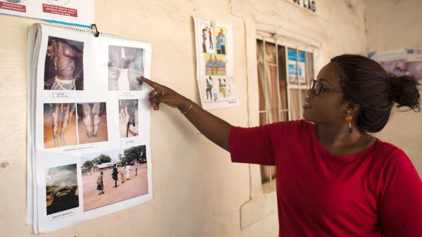 A woman points at a poster which shows the side affects of lymphatic filariasis