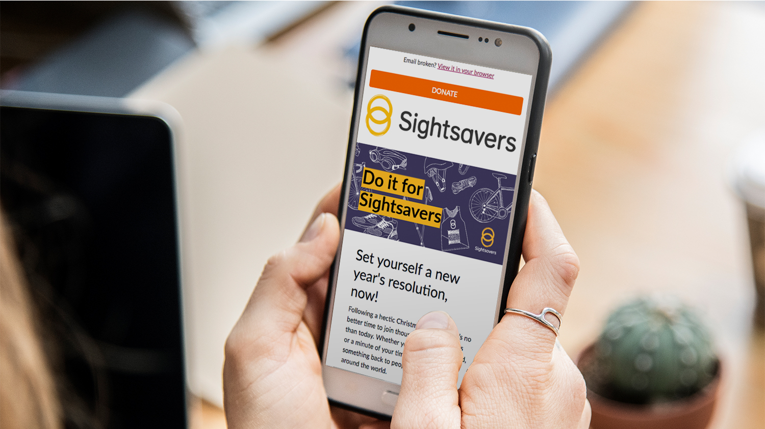 A close-up of someone using a smartphone to read a Sightsavers email.