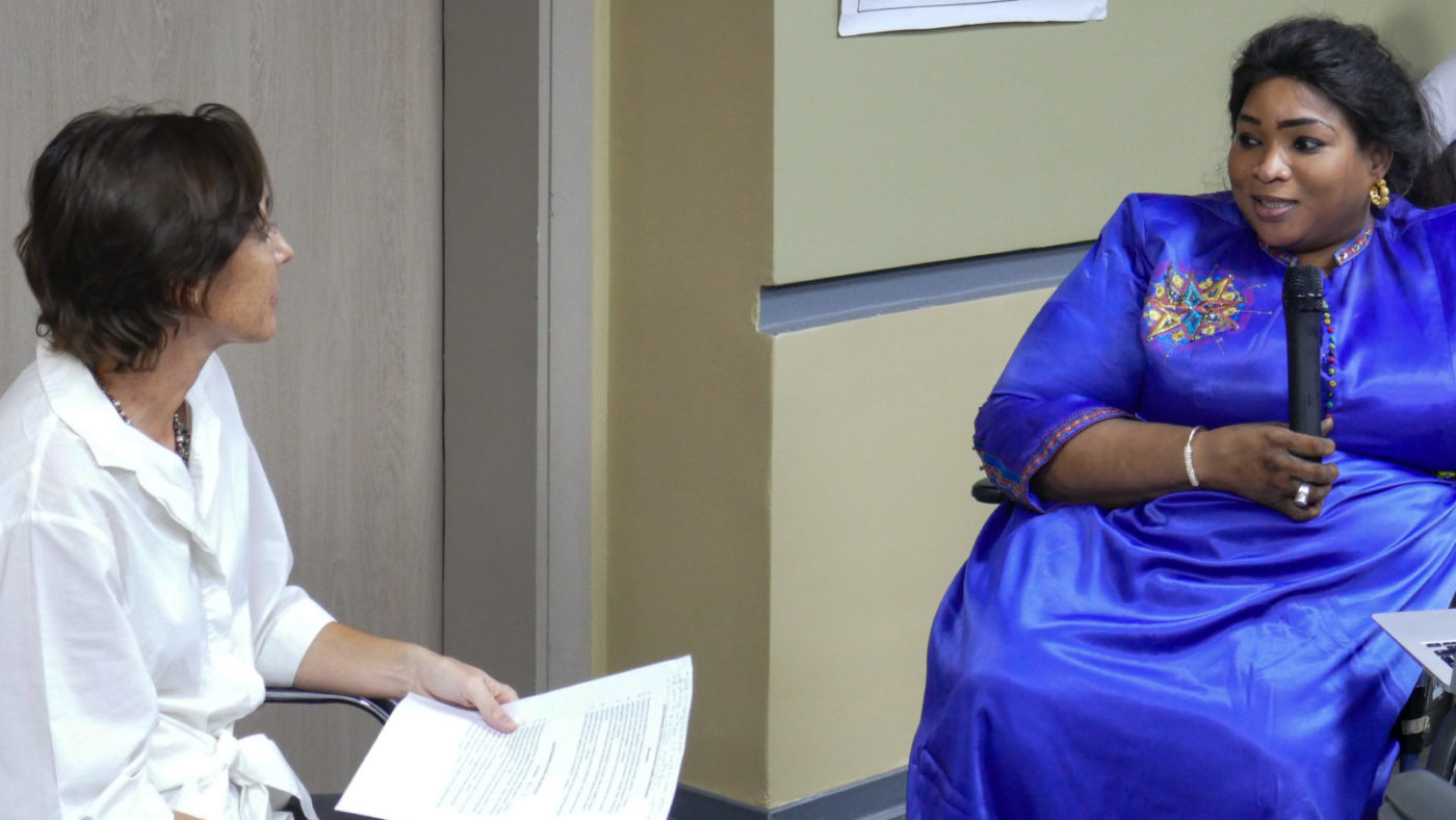 A woman in a wheelchair speaking to another woman.