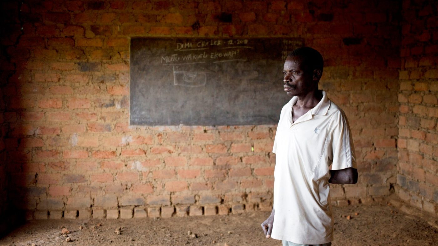 A man stands for a portrait in front of a blackboard at a closed down school.