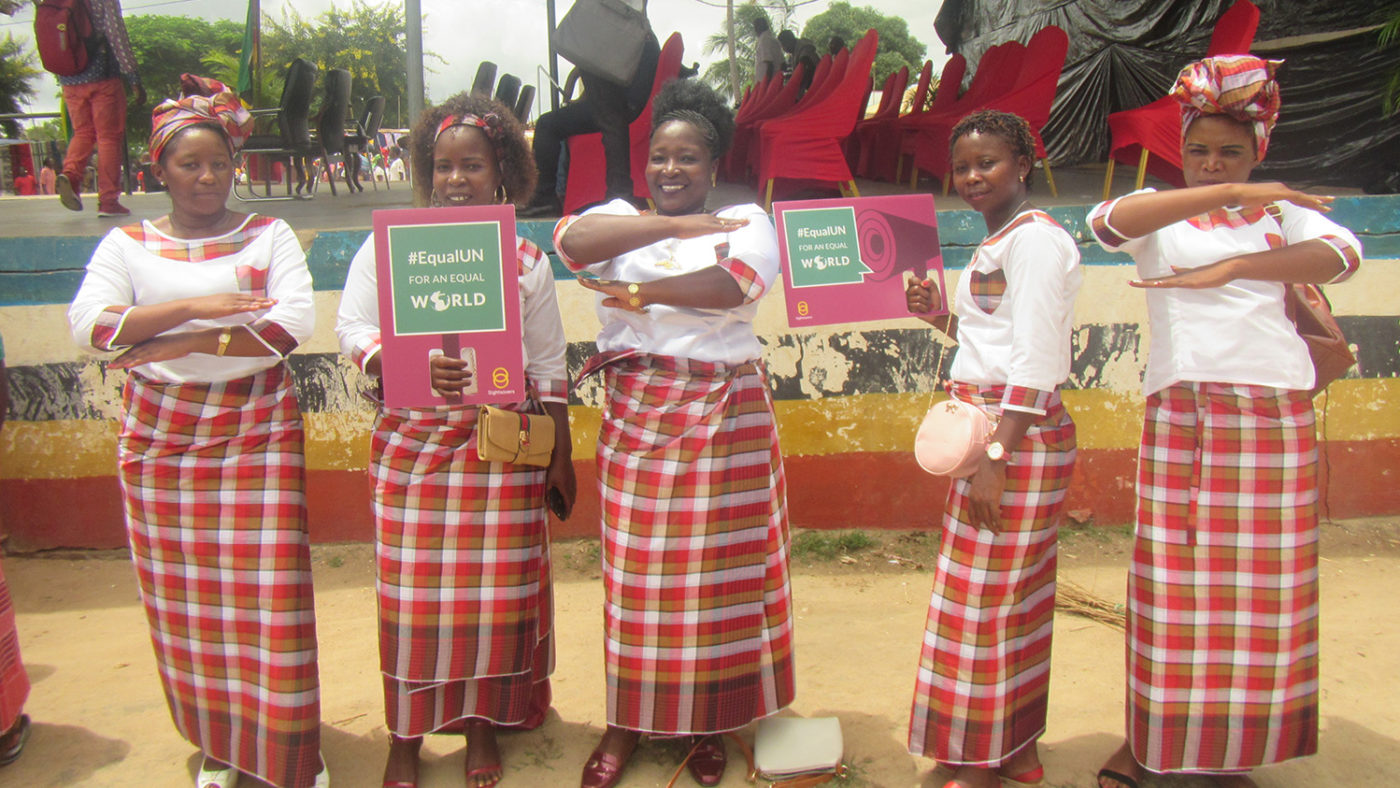 Five women hold signs supporting International Women's Day.
