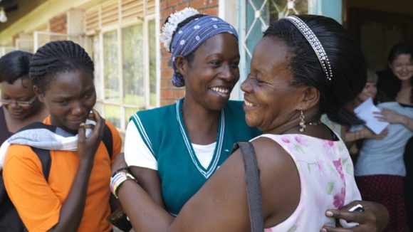 Two women embracing and smiling, outside.