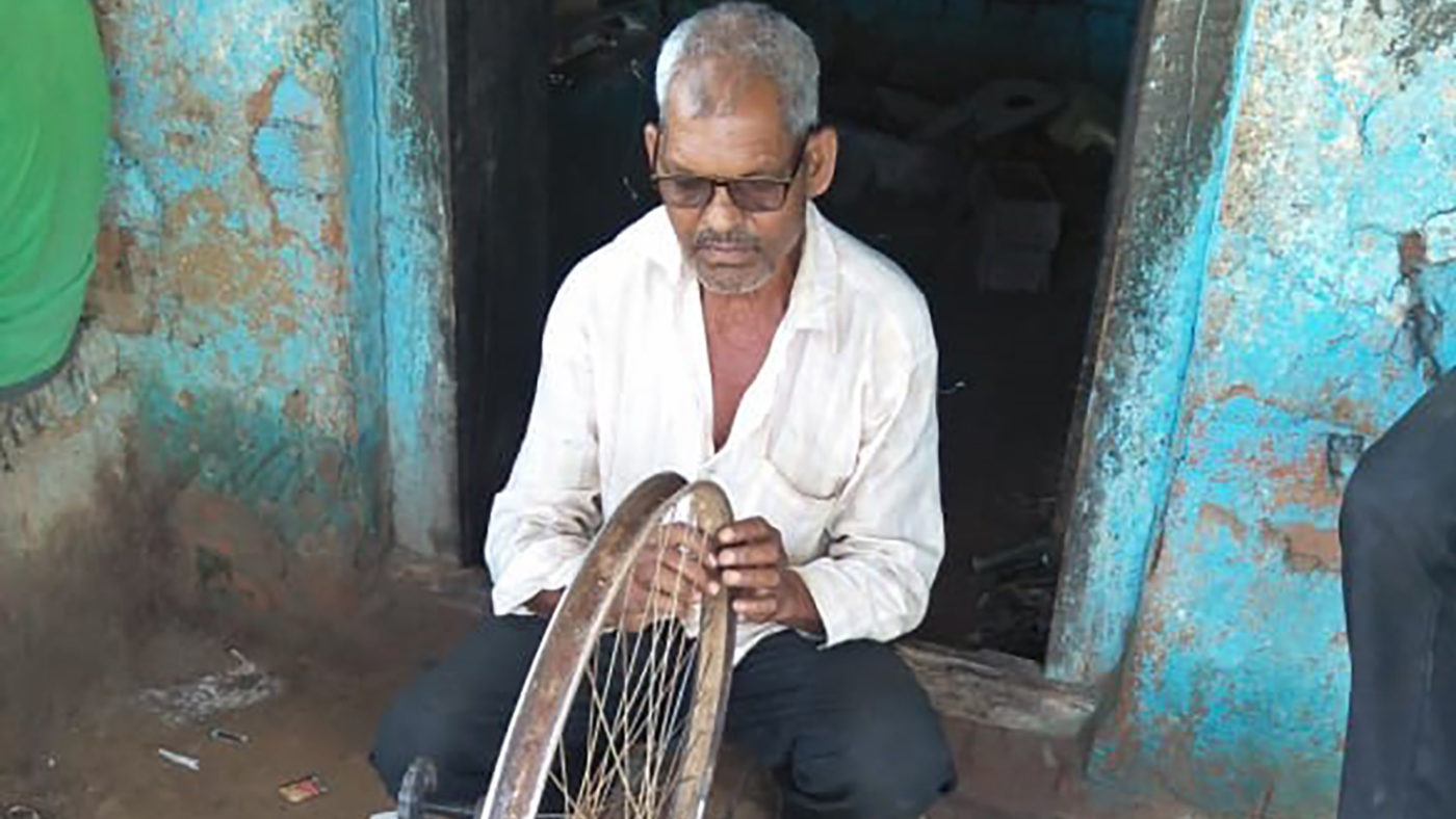 A man fixes a bicycle wheel.