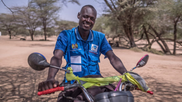 A man smiling while sat on a motorbike.