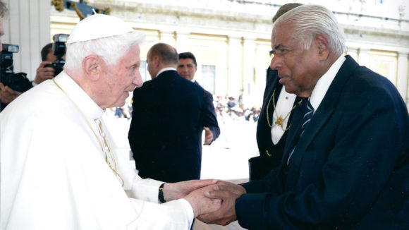 The Pope holds hands and greets another man.