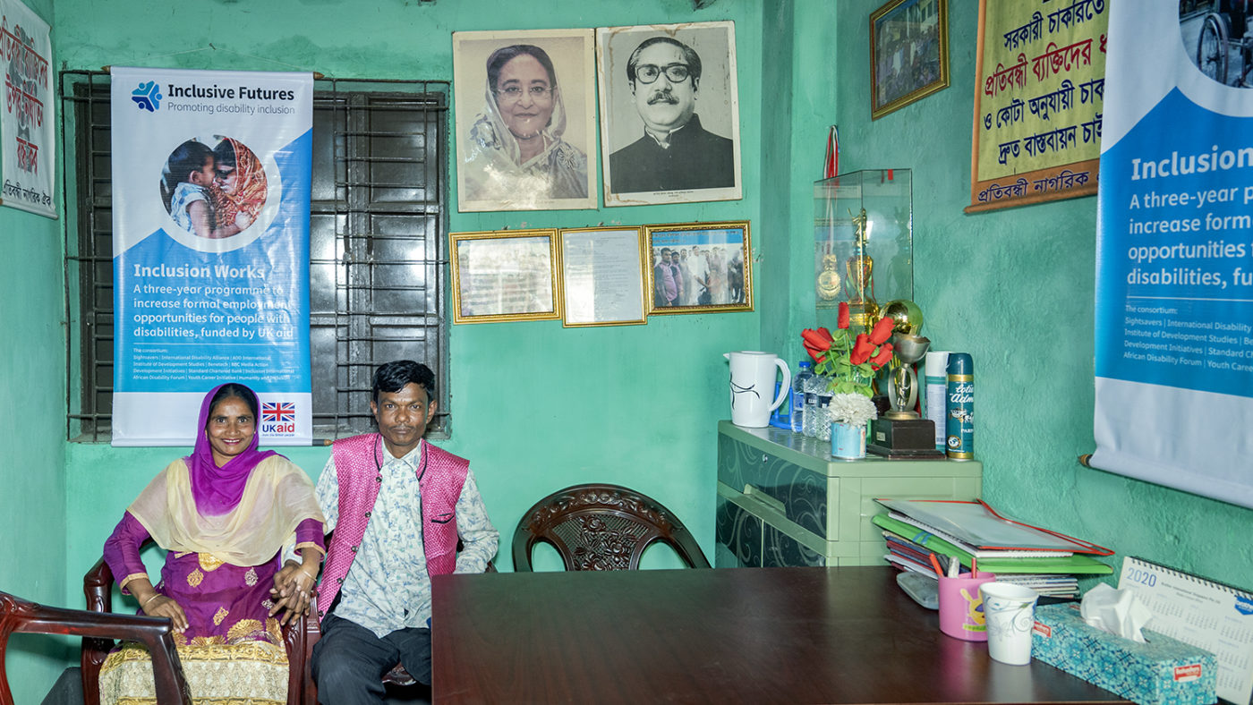 A man and woman hold hands while sitting in an office.