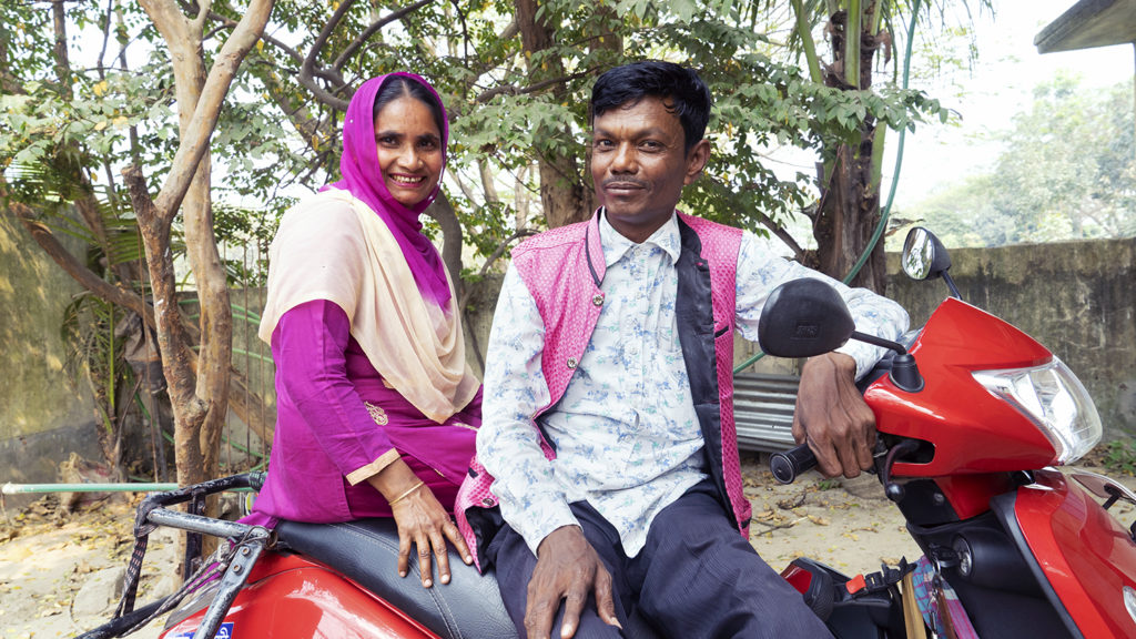 A man and wife sit on a motorbike.