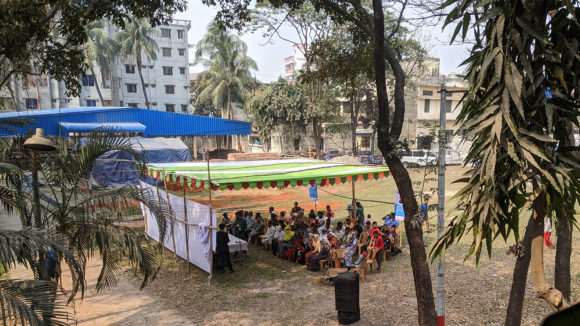 An outdoor meeting in a grass courtyard.