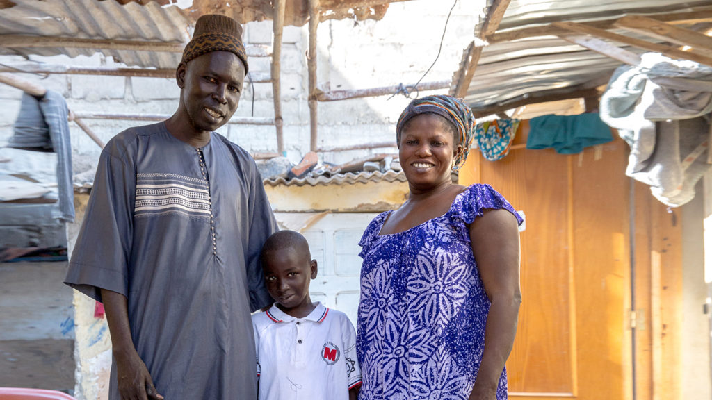 A man and women sit smiling, with their son in between them.