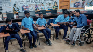 Students using assistive technology with a teacher using a wheelchair.