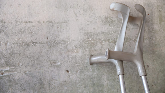 A pair of crutches leaning against a grey wall.