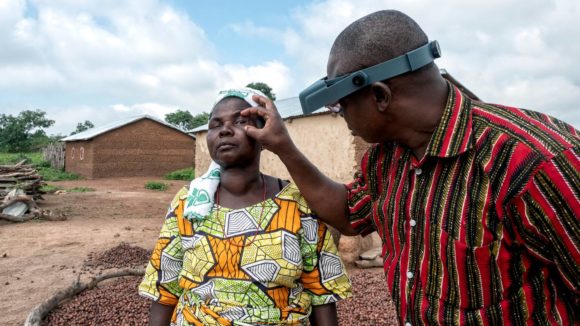 A male ophthalmologist checks a woman's eyes for signs of trachoma.