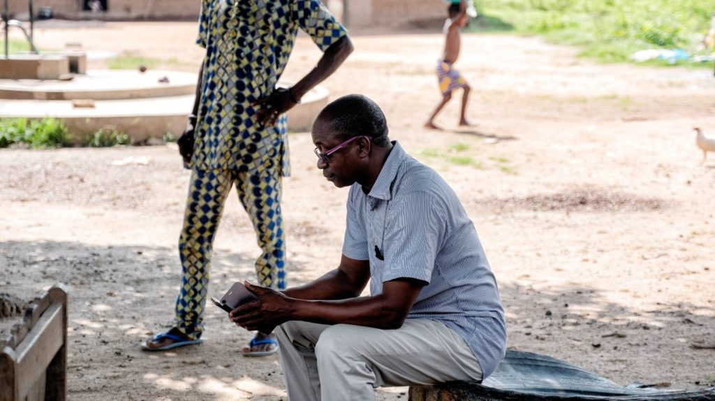 A man sits outside and uses his mobile phone.