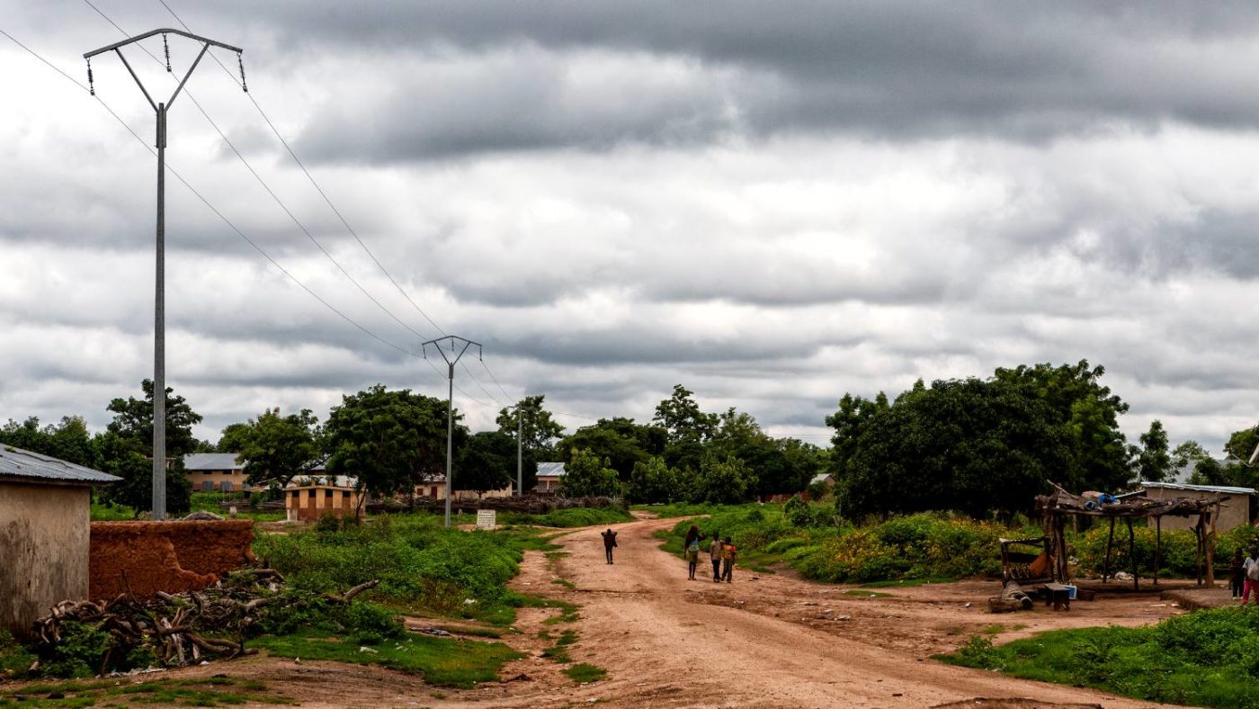 Community members walk down a long dirt road in rural Benin.