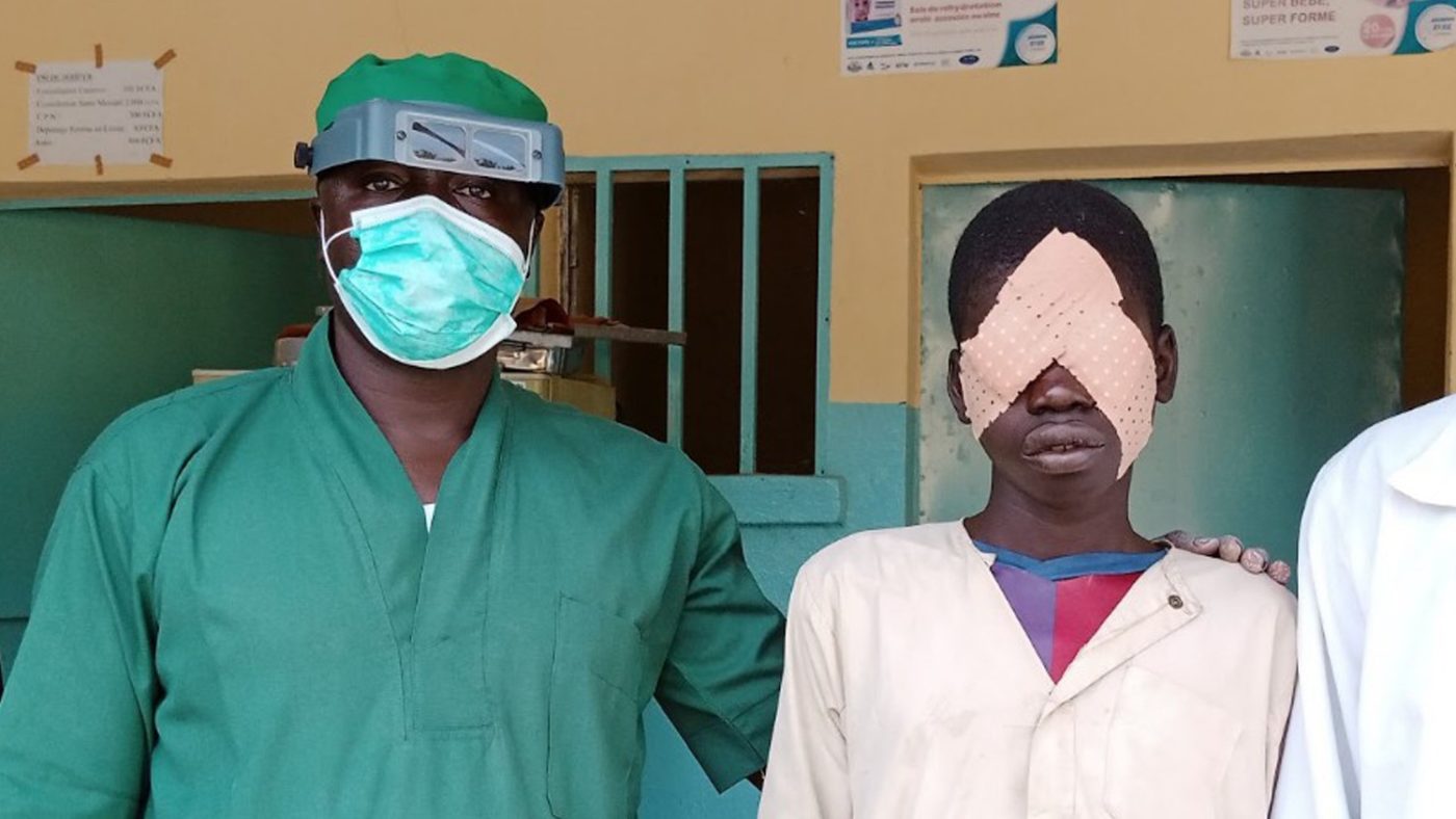 Boy ready for surgery, standing with surgeon.