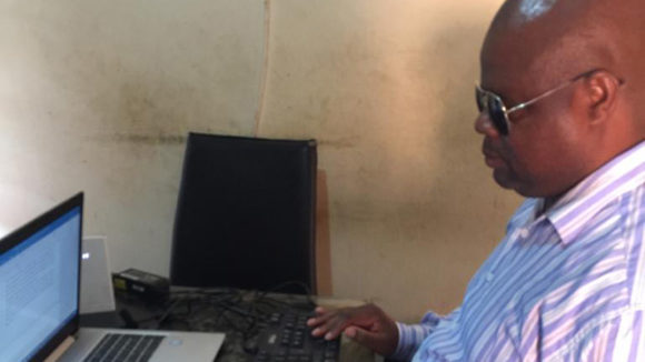 Thomas Mtonga sitting at his laptop.