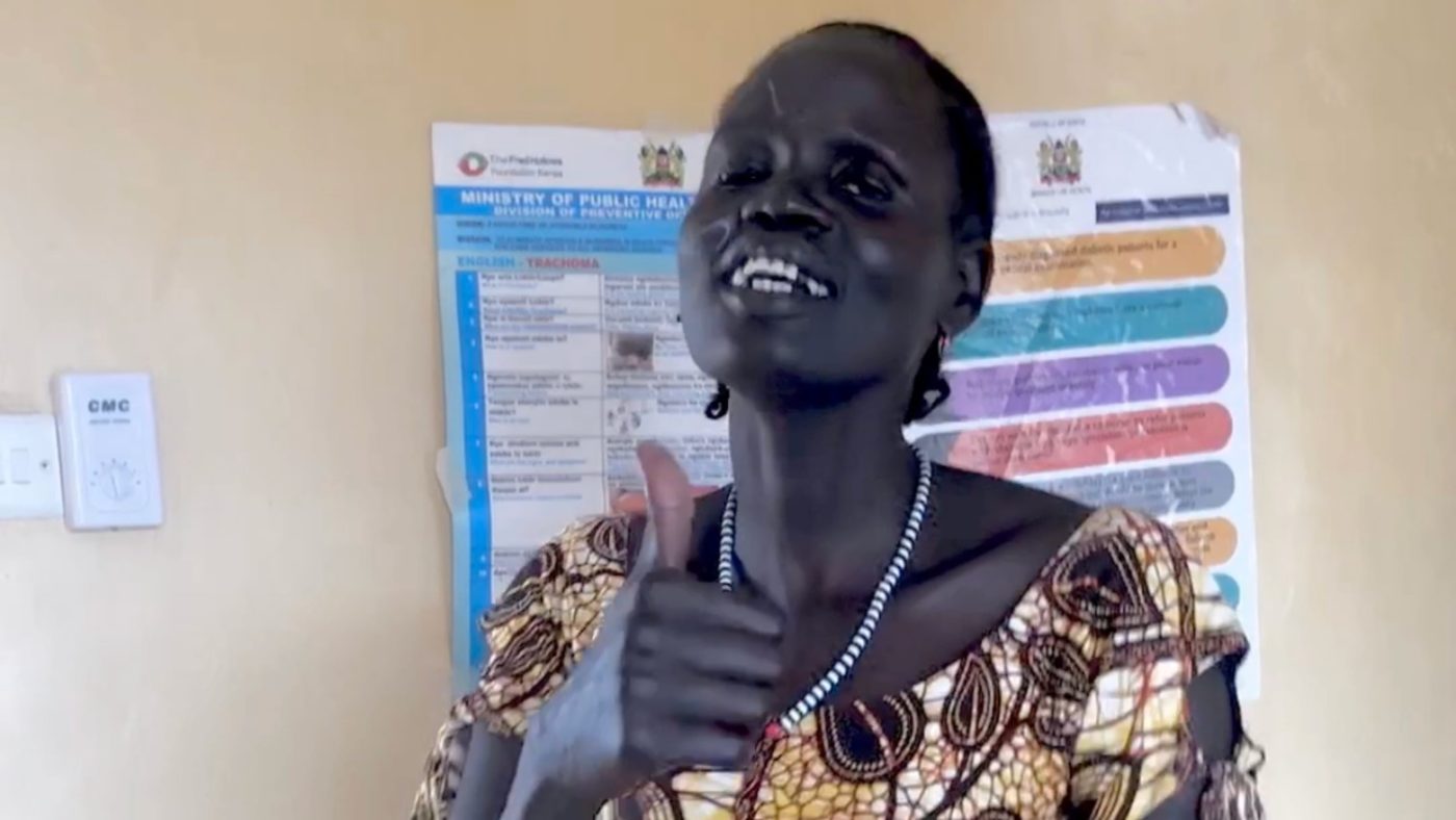 A woman smiles and gives a thumbs up.