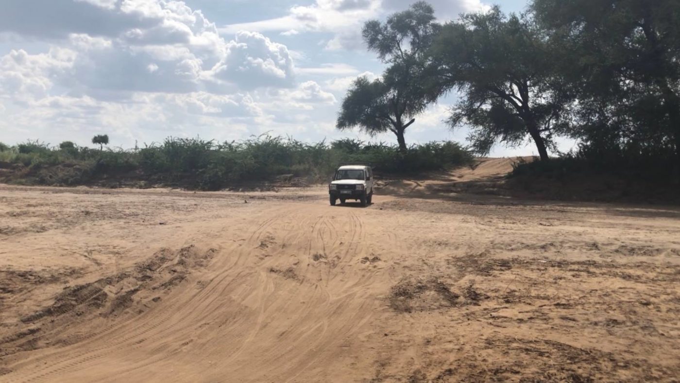 A car travels along a dirt road.