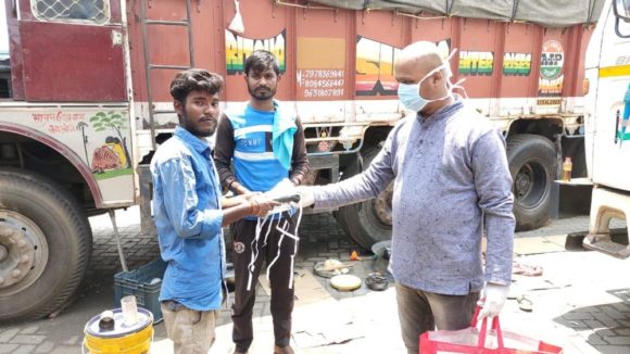 A man wearing a mask hands masks to two other men.