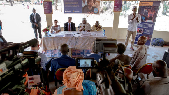 A press conference, with cameras pointing at a top table with speakers.