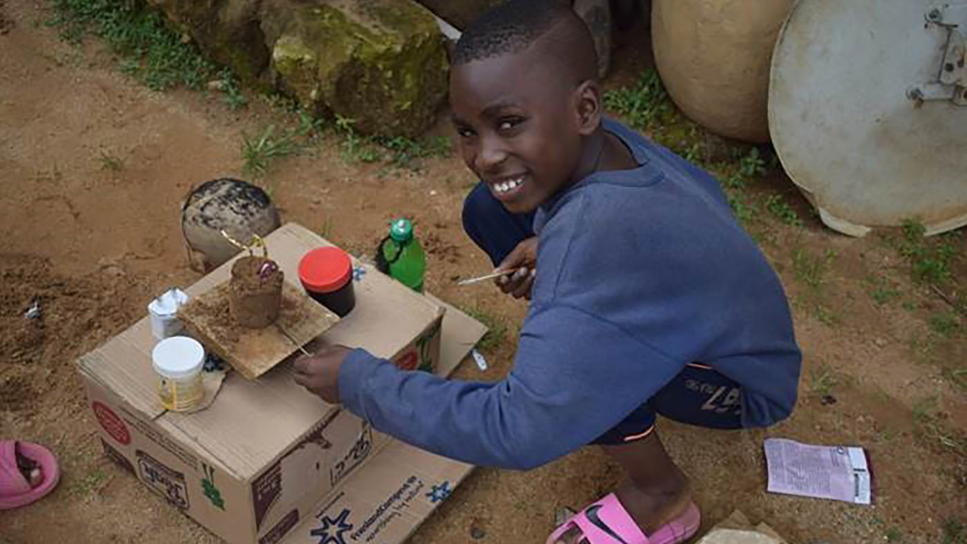 A boy smiles as he plays with his toys outside.