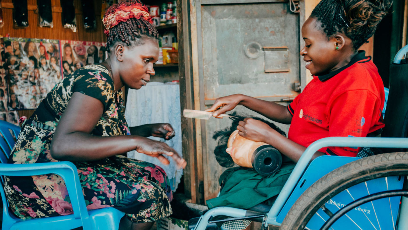 two women sit together talking. One is sitting in a wheelchair.