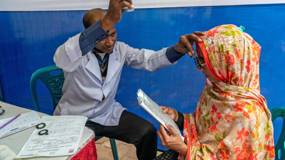 A doctor checks a pair of glasses on a women.