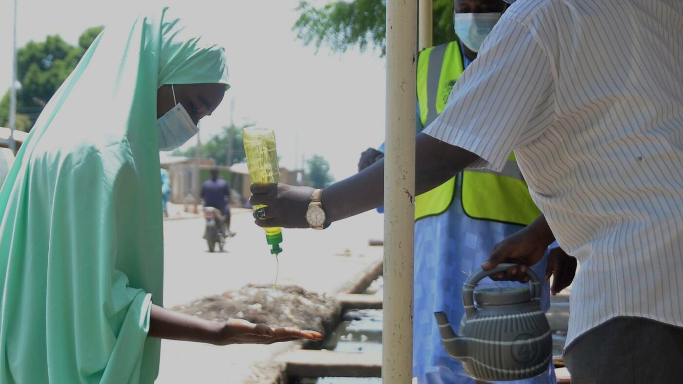 Volunteer distributor wears mask and washes hands before giving out treatment.