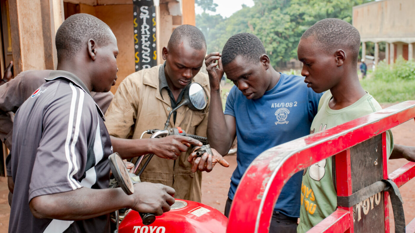 Four men stand around a car.