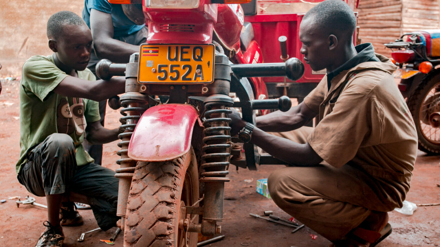Two men fix a motorcycle.