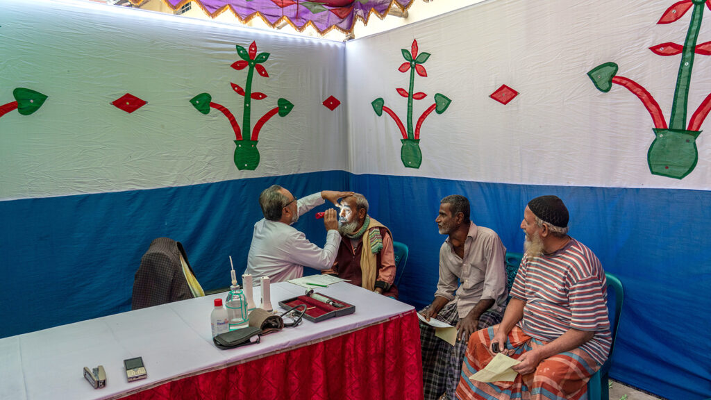 A doctor shines a torch into a man's eye.