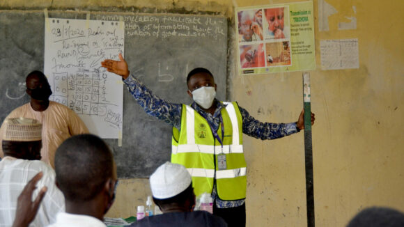 A man wearing a mask gives a demonstration to distributors in a school classroom.