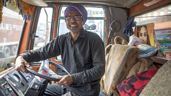 A man with glasses, smiling while sat in his truck.