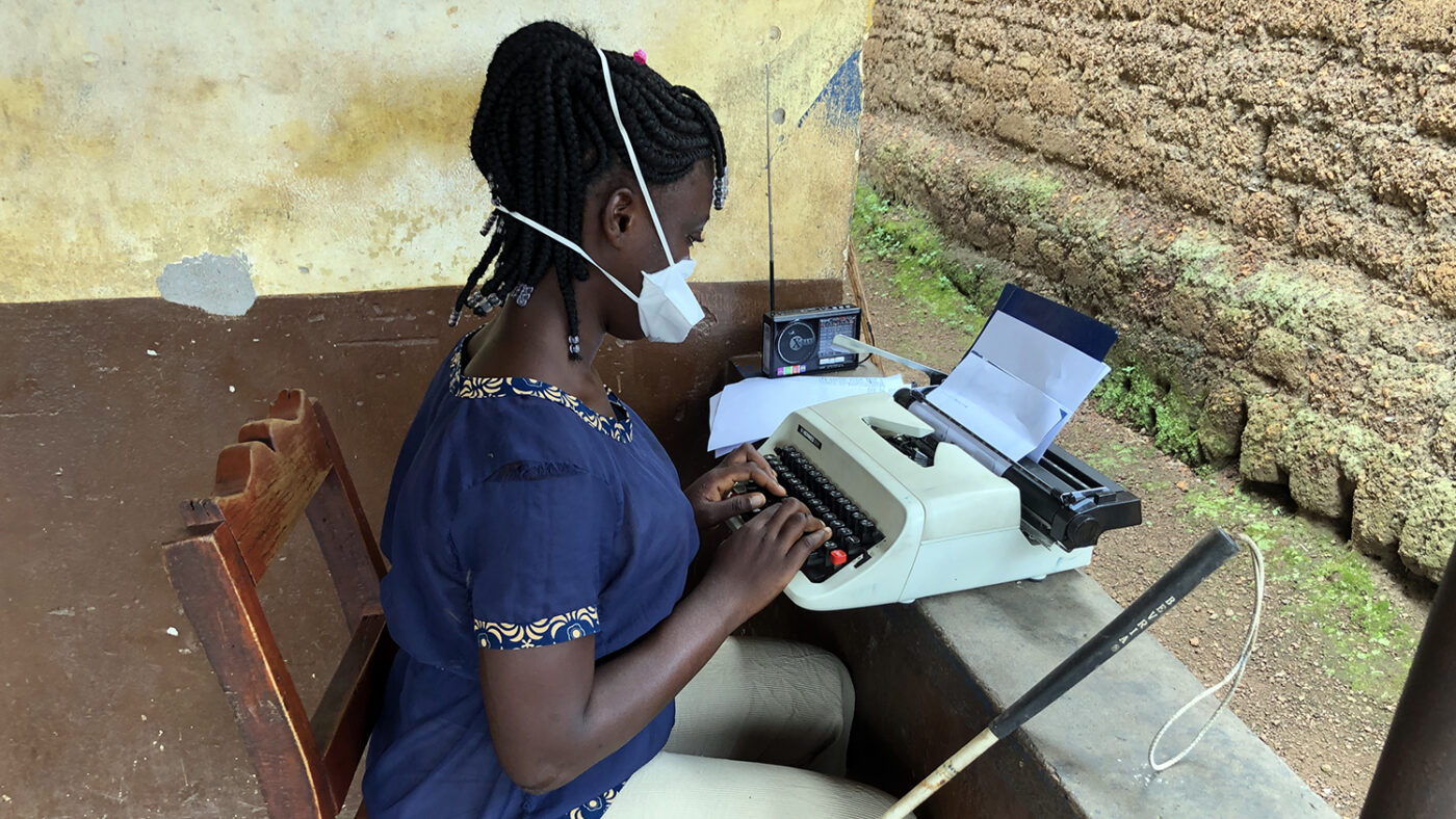 A girl with a face mask sits outside listening to a radio.