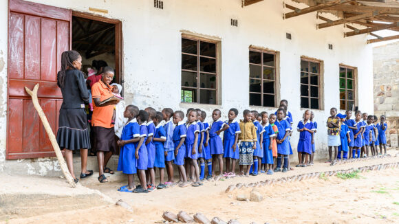 A queue of children waiting outside a building during a mass drug administration.