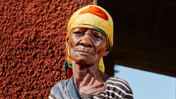 A woman stands outside next to a wall.