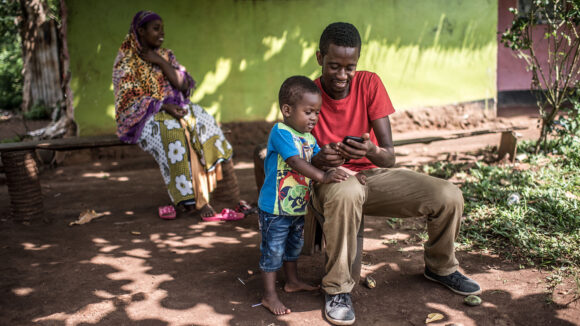 A young boy looks at his father's phone.