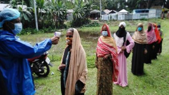 A queue of women line up to have their temperature taken.