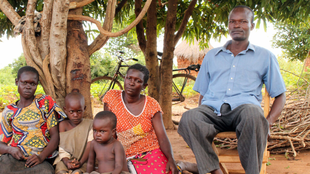 A family sit outside on the ground.