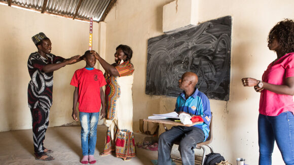 A school-aged boy has his height measured to receive deworming treatment during a school based mass drug administration.