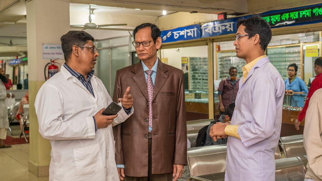 Three men talking in the lobby of a hospital.