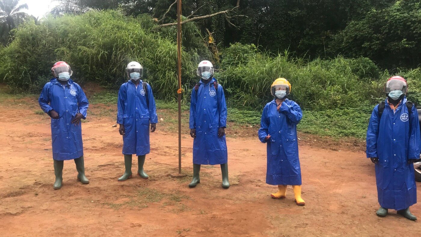 Five people dressed in protective clothing stand outside.
