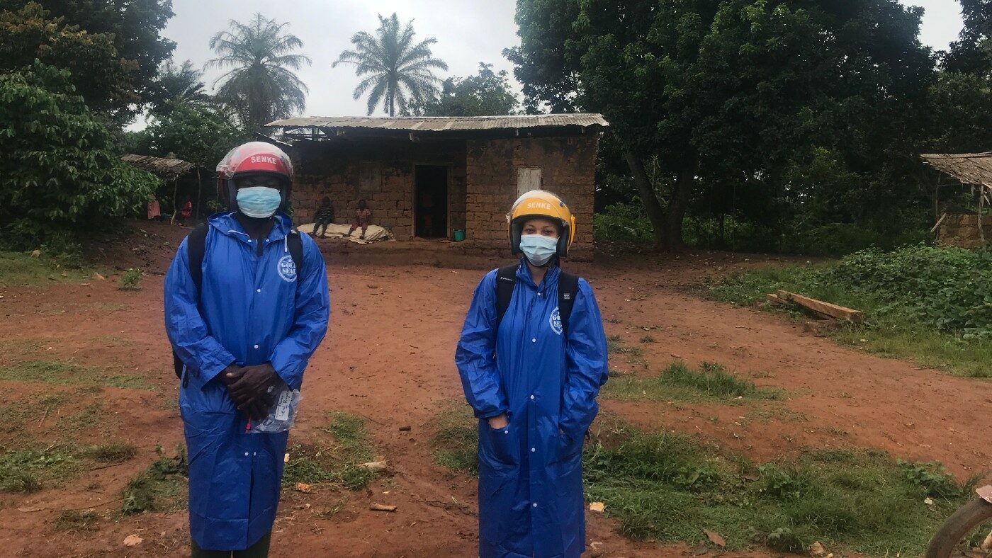 Two people standing outside in protective clothing.