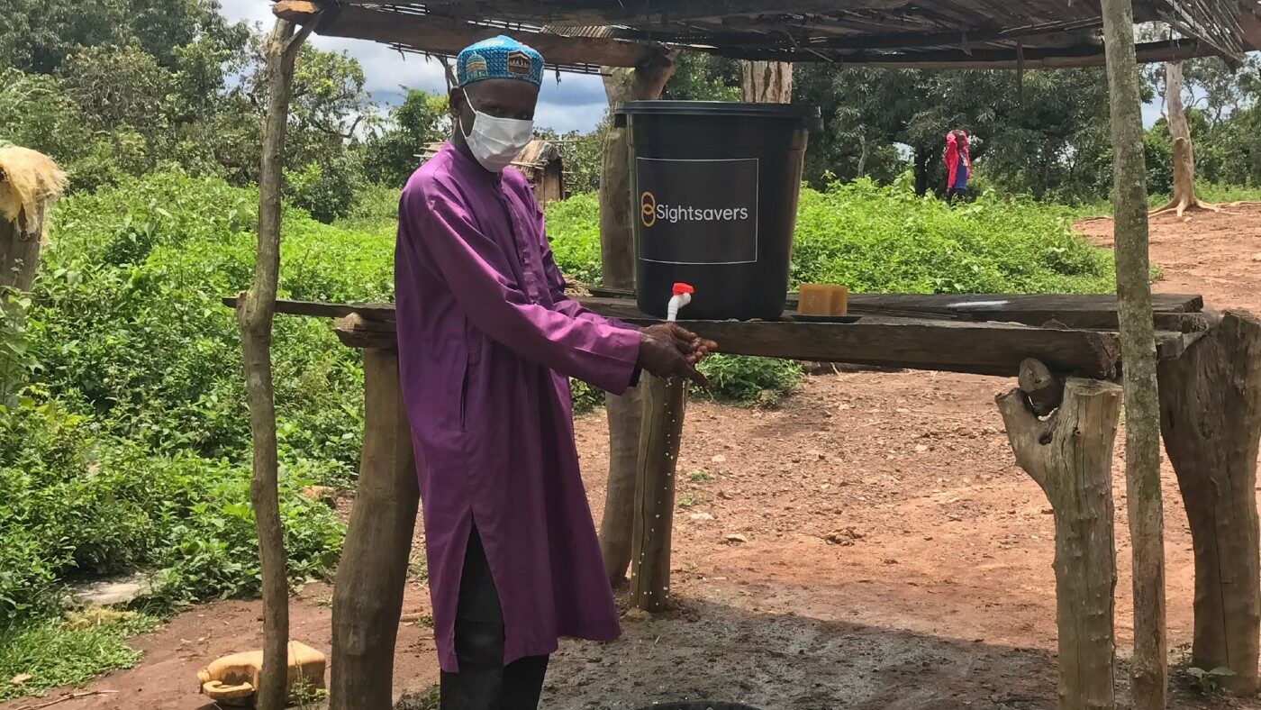 A man washing his hands outside using a tap.