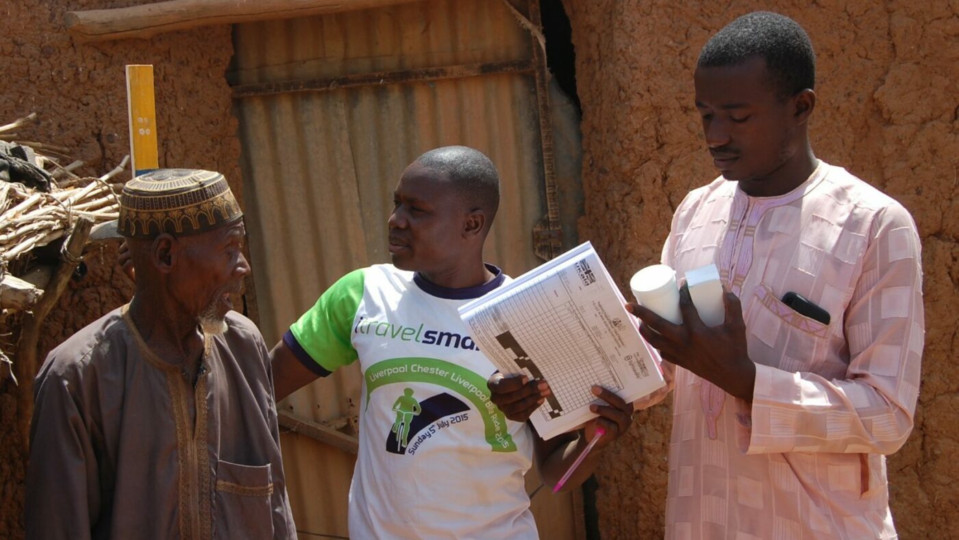A man is measured against a dole pole to determine how much lymphatic filariasis treatment he needs.