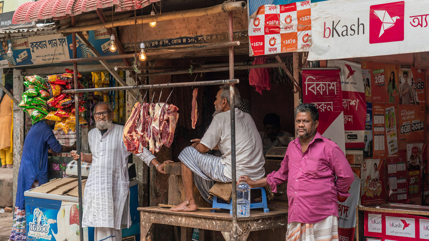 Men standing next to a raw meat stand.
