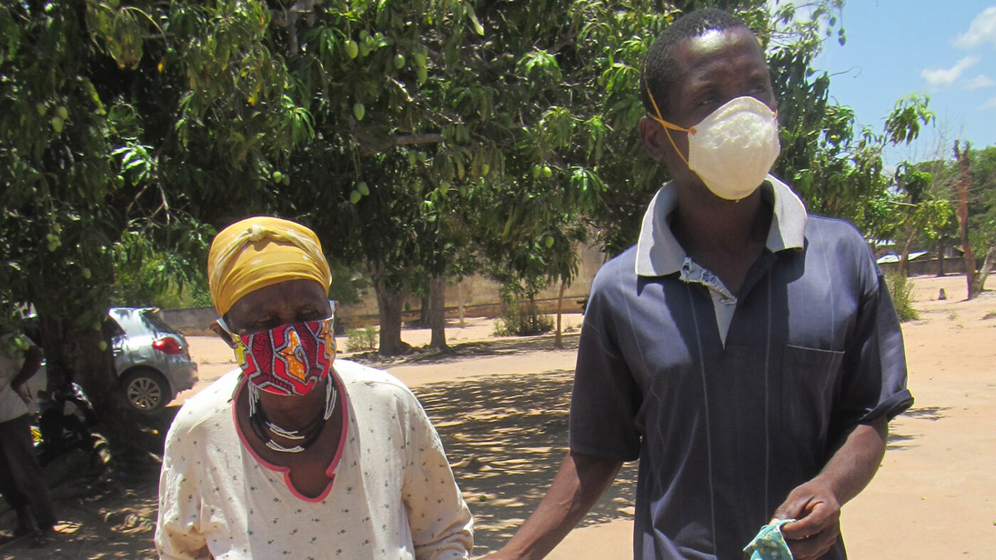 A man escorts an elderly lady down a path.