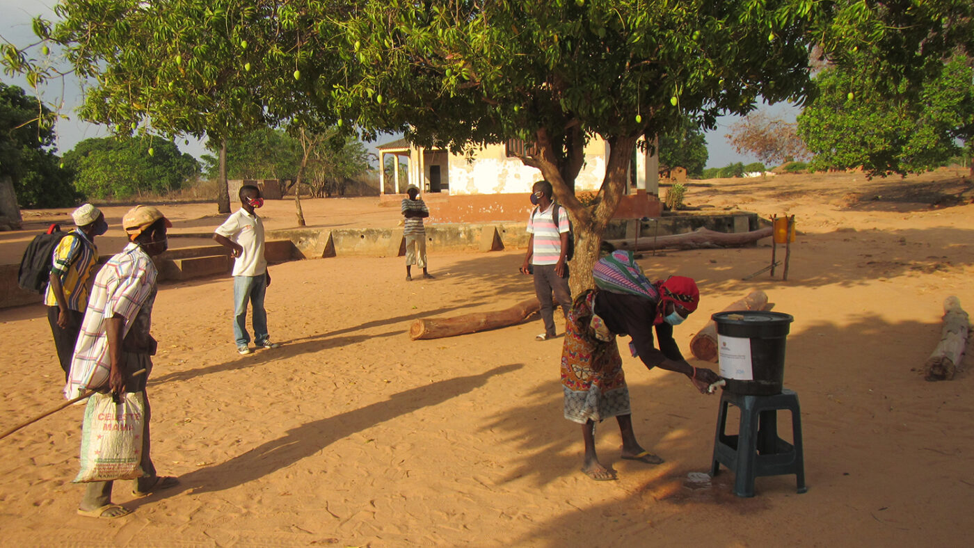 People wash their hands using a makeshift tap.